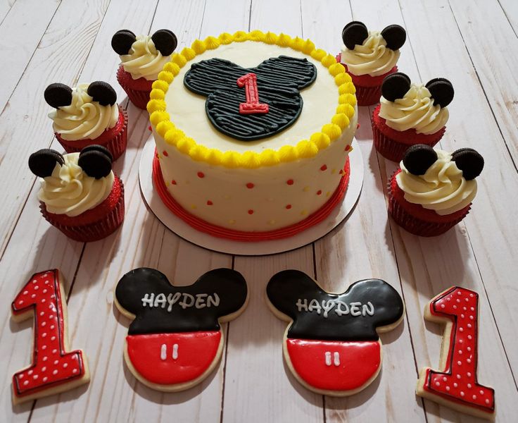 a mickey mouse cake and cupcakes with the number one on them for 1st birthday