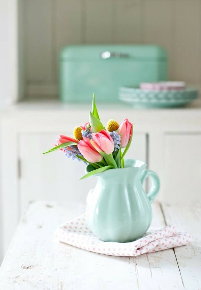 a vase filled with flowers sitting on top of a wooden table next to a plate