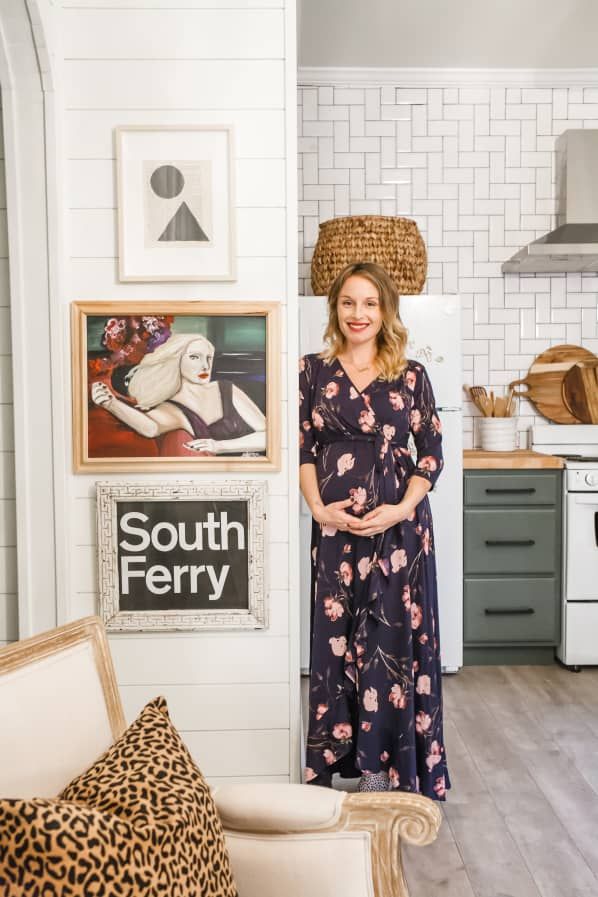 a woman standing in a kitchen next to a wall with pictures and posters on it