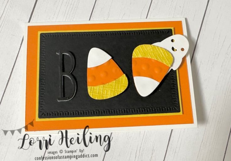 an orange and black halloween card with candy corn on the front, and letter b in the middle