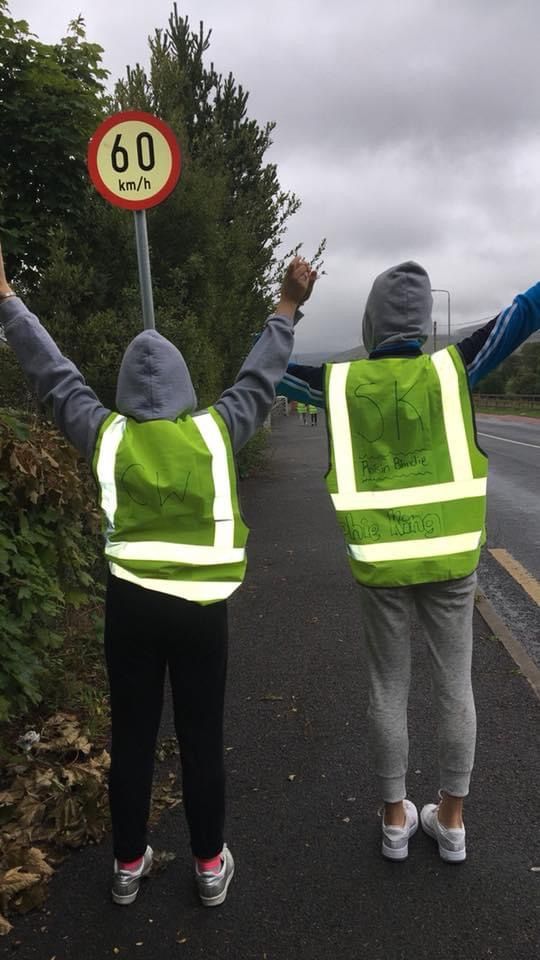 two people in safety vests holding their hands up while standing on the side of a road