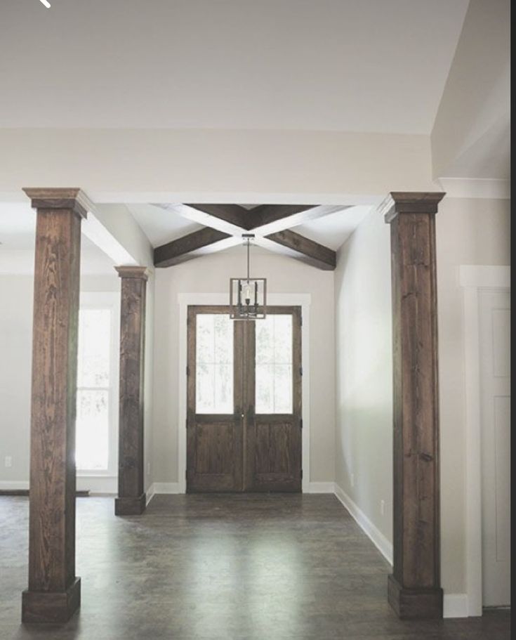 an empty room with two wooden pillars and a chandelier hanging from the ceiling