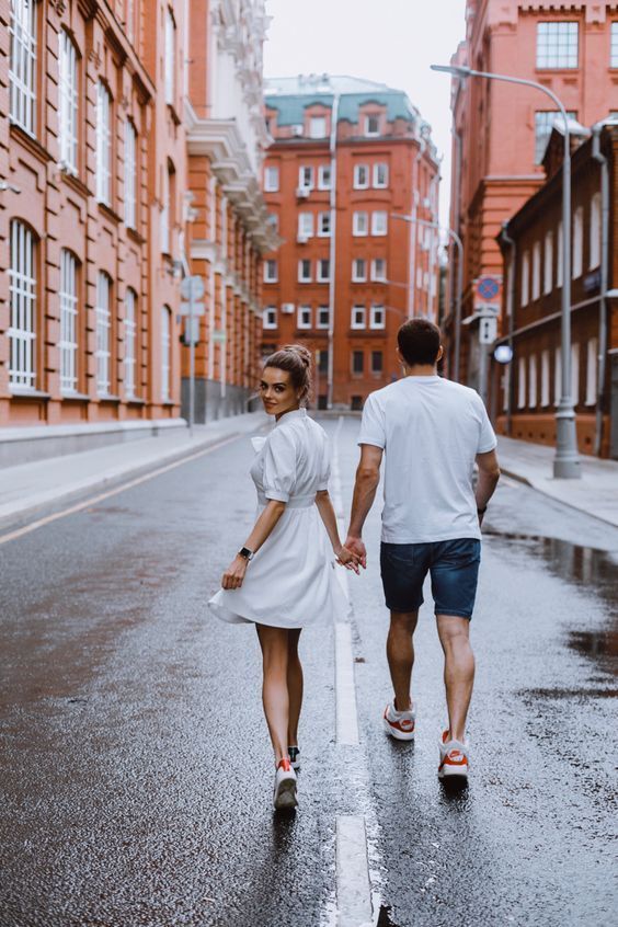 a man and woman walking down the street in the middle of the city on a rainy day