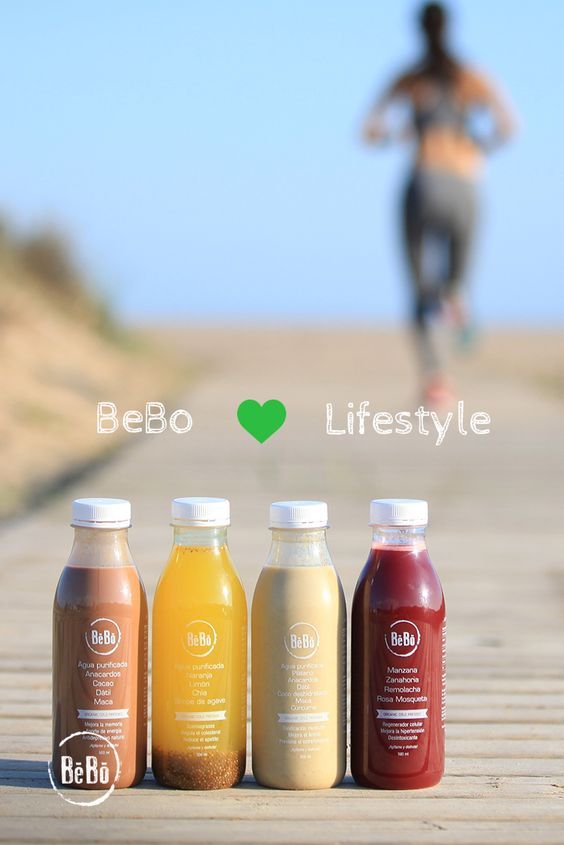 three bottles of juice sitting on top of a wooden table next to a person running