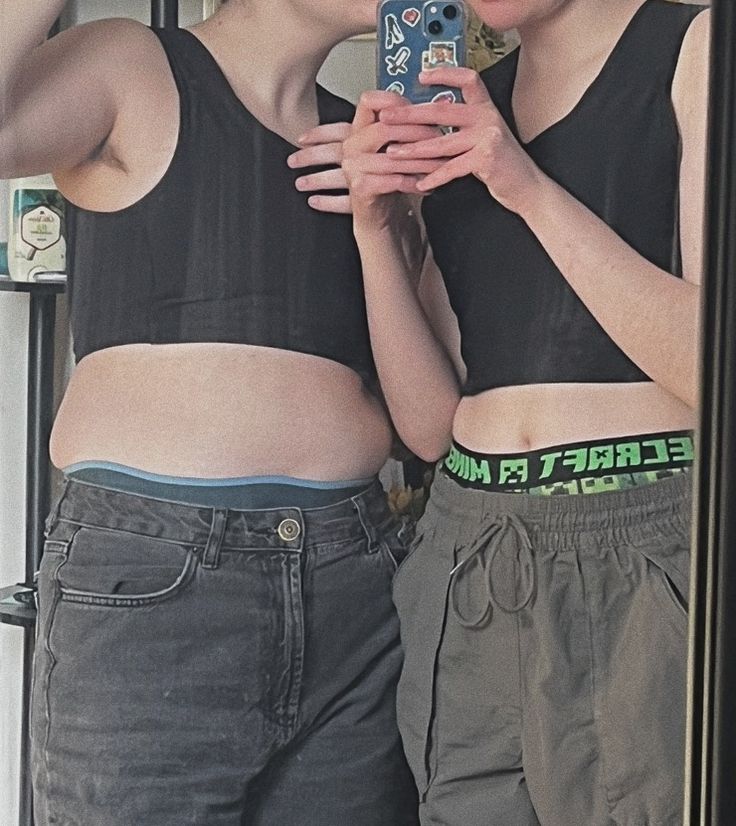 two women standing next to each other in front of a mirror