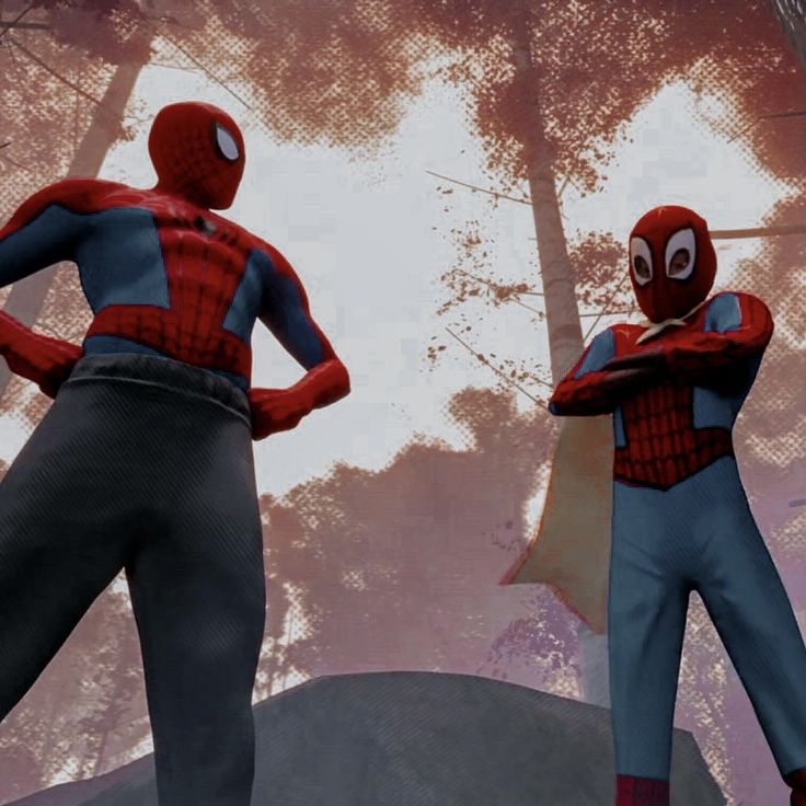 two spider - man standing next to each other in front of trees