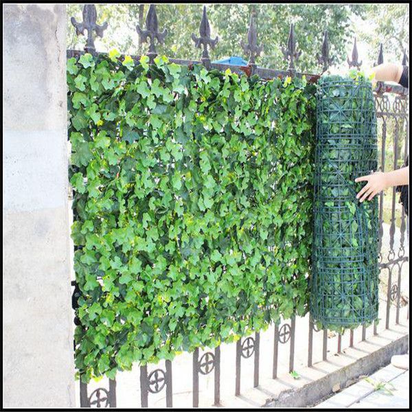 a person is reaching for a green privacy panel on the side of a fenced in area