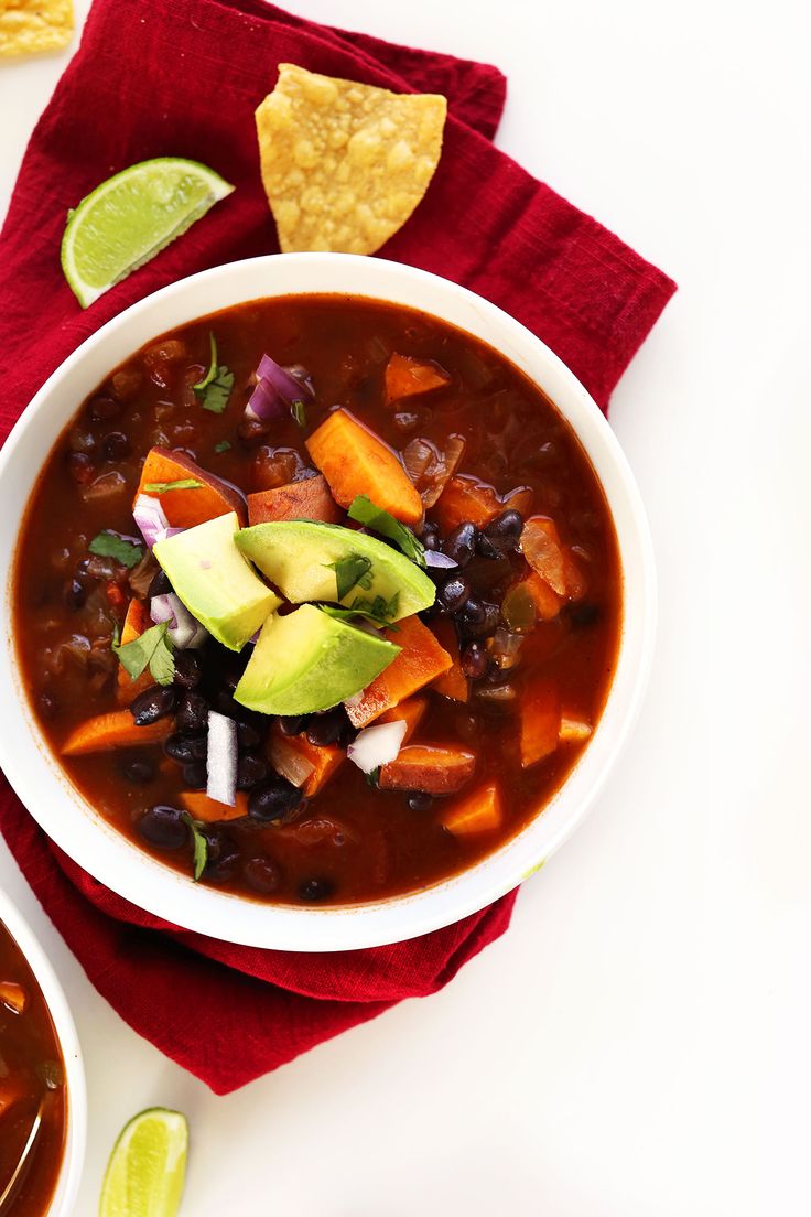 two bowls of soup with tortilla chips and avocado on the side