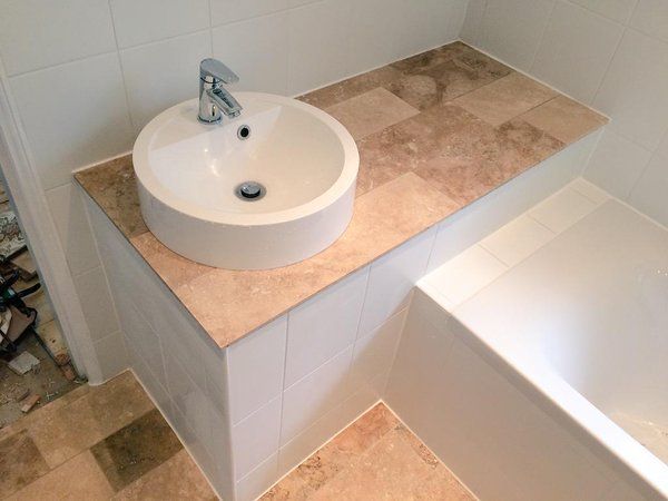 a white sink sitting on top of a counter next to a bath tub