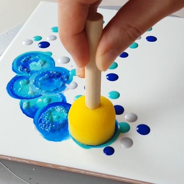 a hand is picking up something from a blue and yellow object on a white surface