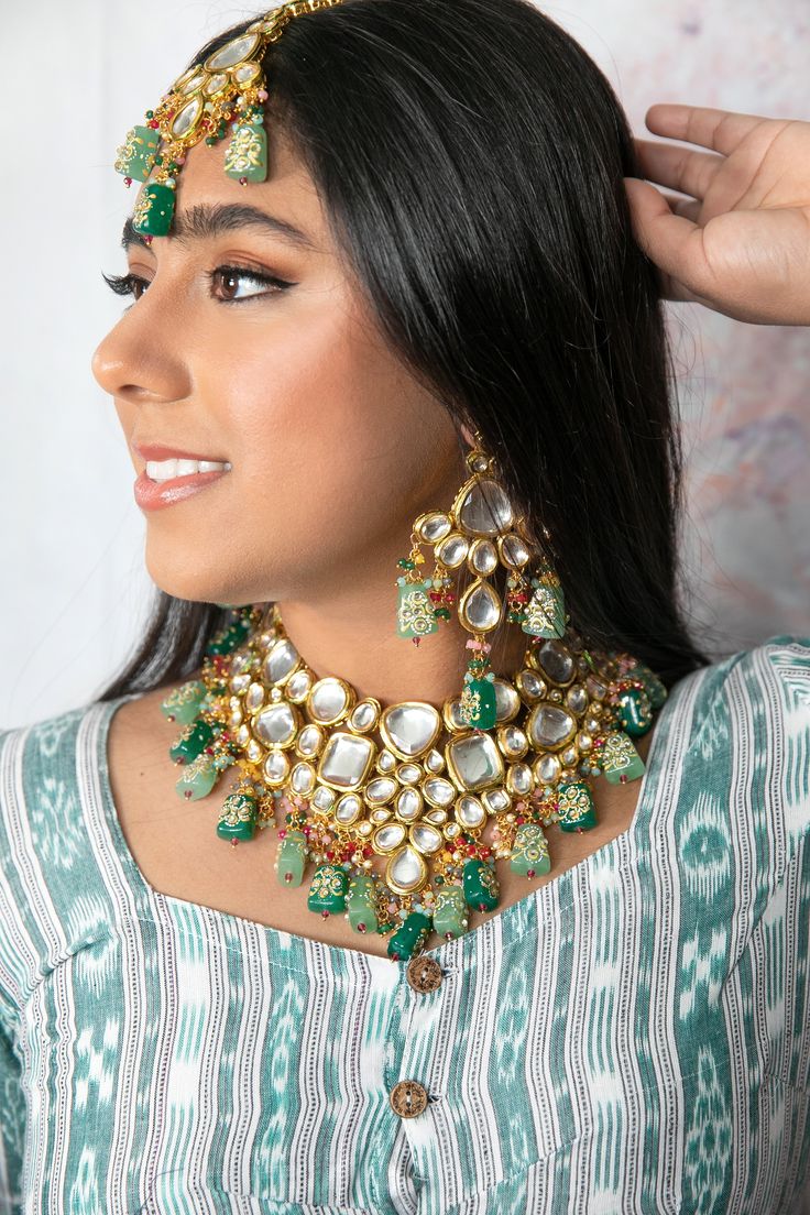 The Mahika Jewelry set is a handmade beauty. With its name meaning "earth" in Sanskrit this divine piece lives up to all expectations. Consisting of hand painted back meenakari, premium quality kundan, and mint and emerald handpainted Tanjore beads this lovely set is a must have in everyone's jewelry collection. Specifications Materials used: Kundan, Hand-painted Mint and Emerald Tanjore beads with back Hand-painted back Meenakari Weight: Necklace- 180 g, Earrings- 41.8 g, Tikka- 43.4 g At Romik Cheap Festive Meenakari Jewelry, Luxury White Meenakari Necklace, Luxury Spiritual Meenakari Necklace, Chandbali Meenakari Necklaces For Rituals, Meenakari Chandbali Necklaces For Rituals, Meenakari Chandbali Necklace For Rituals, Festive Green Kundan Necklace With Mirror Work, Spiritual Kundan Necklaces For Festive Occasions, Festive Meenakari Necklaces For Rituals