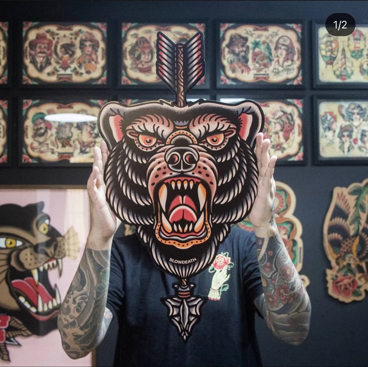 a man holding up a bear mask in front of his face with tattoos on it