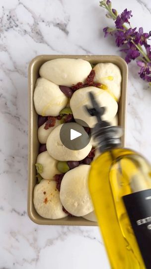 a bottle of olive oil next to some sliced up bananas and grapes in a bowl