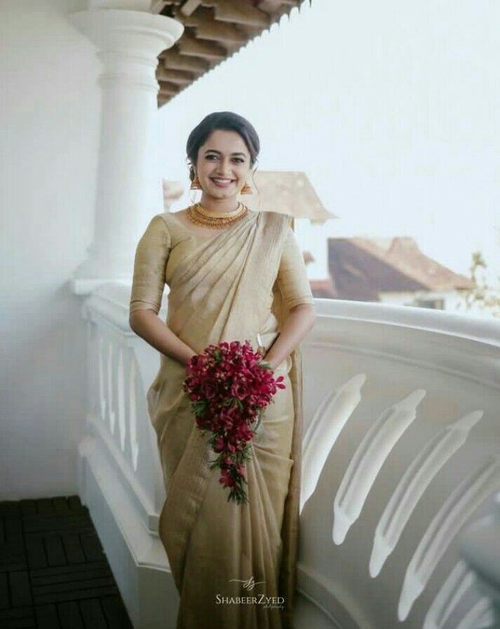 a woman is standing on a balcony with flowers in her hand and wearing a sari