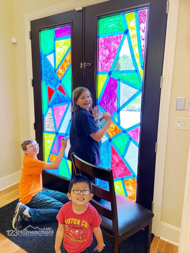 two children are standing in front of a stained glass door and another child is sitting on the floor