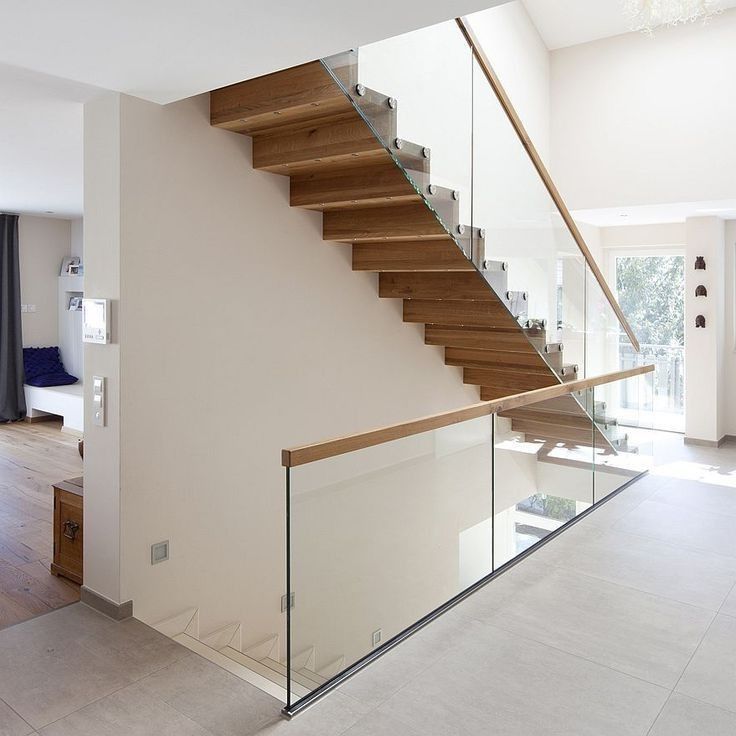 a staircase with glass railing and wooden handrail