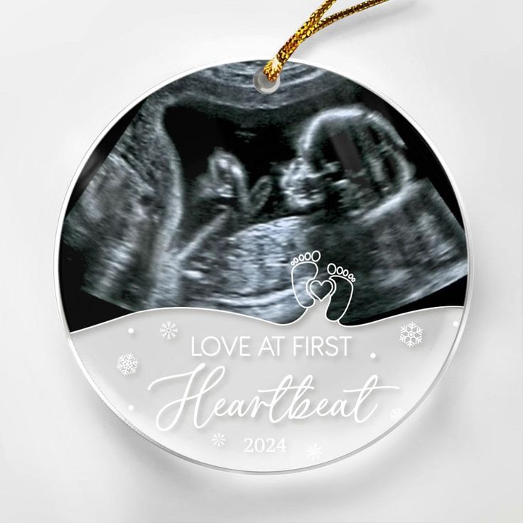 a round ornament with the words love at first and an image of a baby's feet