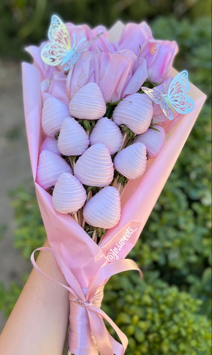 a person holding a bouquet of flowers with butterflies on it's wings in their hand