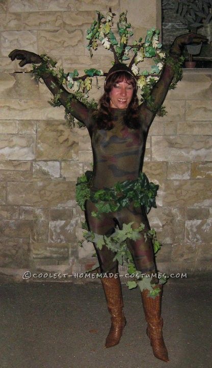 a woman dressed in costume standing next to a brick wall and holding her arms up