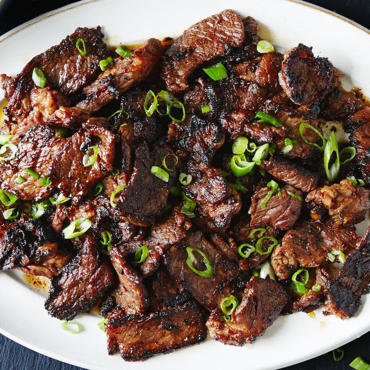 a white plate topped with meat and green onions