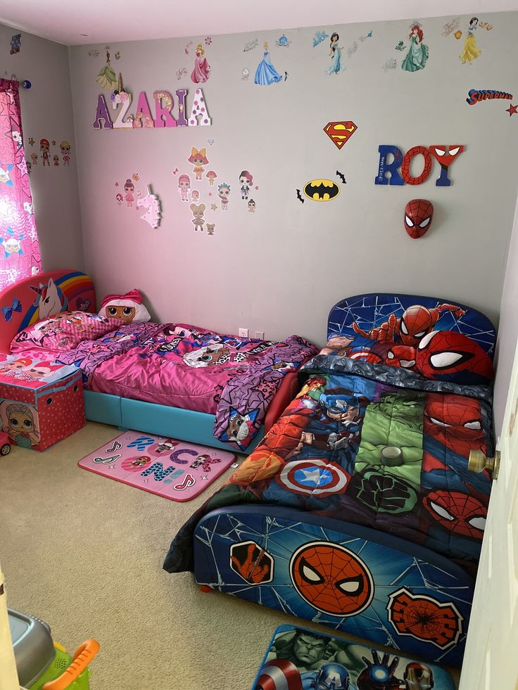 two beds in a room with spiderman decorations on the wall