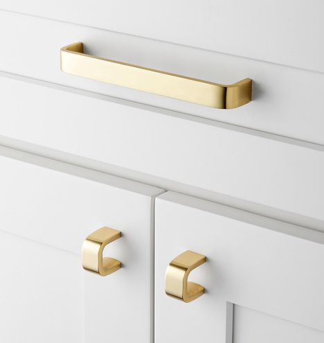 a white dresser with two brass handles and some knobs on the drawer pulls,