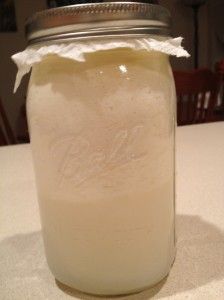 a mason jar filled with liquid sitting on top of a white tablecloth covered table