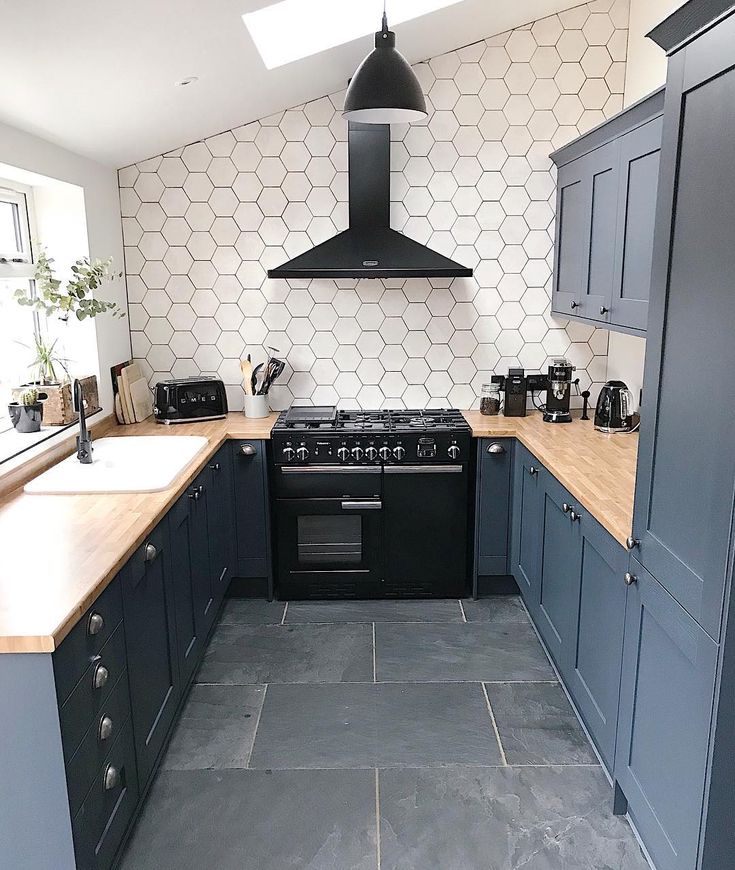 a kitchen with an oven, stove and counter tops in blue painted cupboards next to a white hexagonal wall