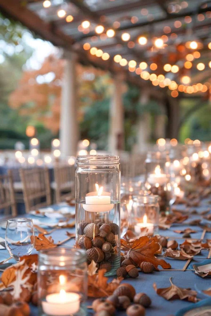 a table with candles and autumn leaves on it is set up for an outdoor dinner