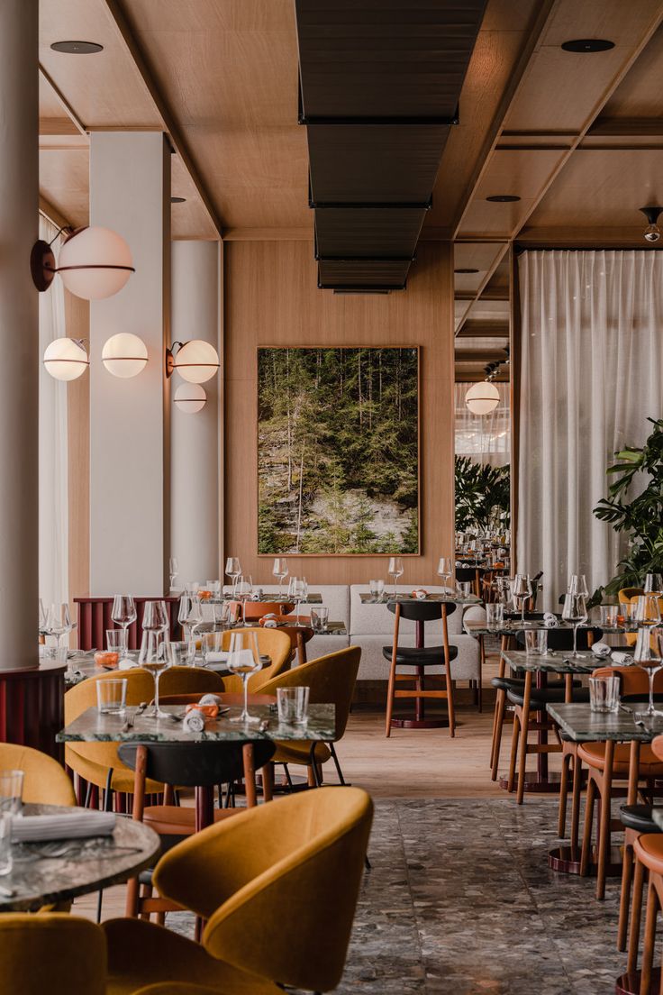 an empty restaurant with yellow chairs and tables