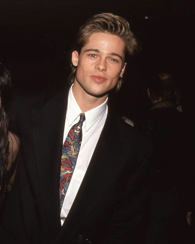 a young man in a suit and tie standing next to a woman at an event