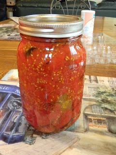 a jar filled with red liquid sitting on top of a wooden table next to magazines