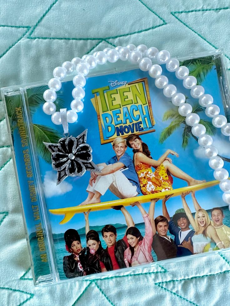 the dvd cover for teen beach movie is shown on a bed with pearls around it