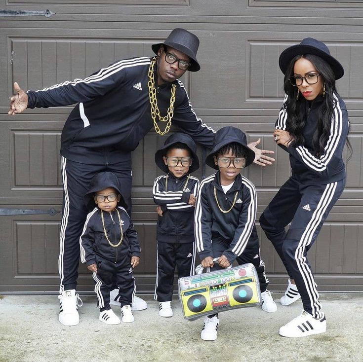 a group of people standing next to each other in front of a garage door wearing matching outfits