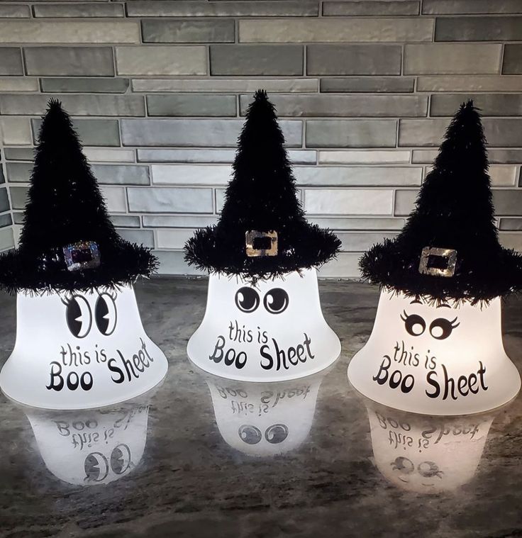 three lighted halloween decorations with black hats and eyeballs on them, sitting on a counter