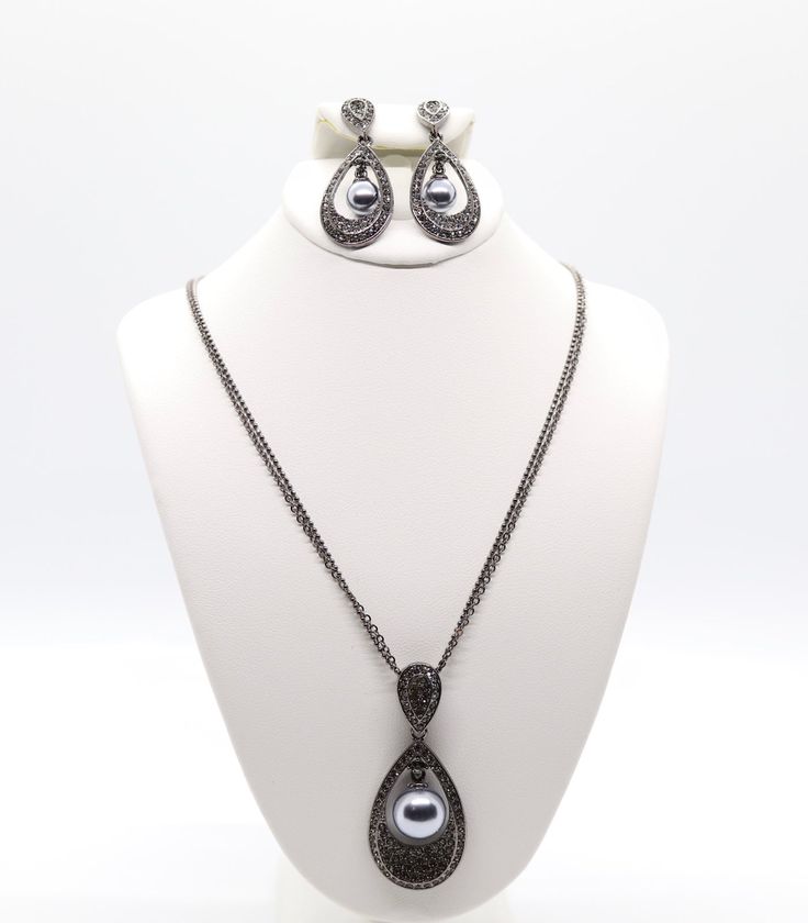 This jewelry set is a beautiful black earrings and necklace with a black pearl in the center. The earrings and necklace are made of high-quality materials and are sure to turn heads. Elegant Jewelry Sets With Teardrop Pendant For Party, Formal Costume Jewelry With Pearl Drop, Metal Drop Earrings For Evening Wear, Teardrop Metal Jewelry For Evening, Evening Teardrop Metal Jewelry, Teardrop Pendant Party Jewelry, Teardrop Pendant Metal Jewelry For Parties, Metal Teardrop Pendant Jewelry For Party, Elegant Metal Jewelry Sets For Evening