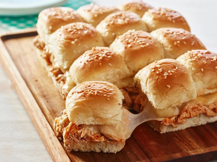 a wooden cutting board topped with chicken sliders