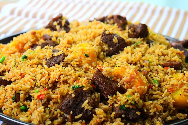 a plate full of rice with meat and vegetables