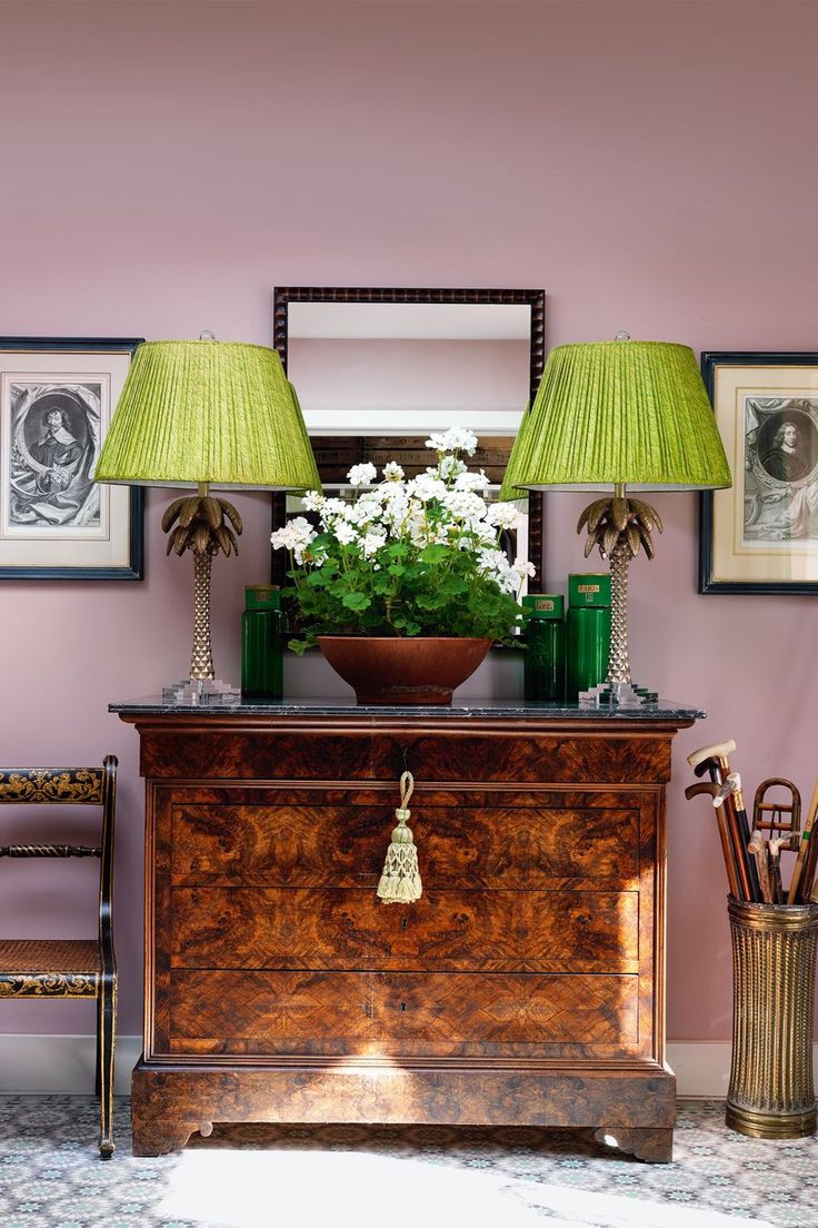 a dresser with two lamps and pictures on the wall above it, along with a green lamp shade