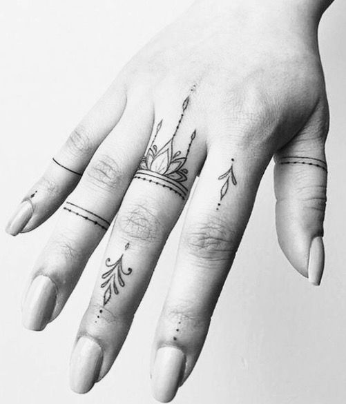 a woman's hand with two different tattoos on her left thumb and one finger