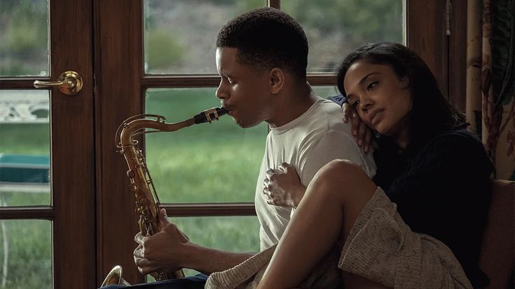 a man and woman sitting next to each other playing saxophone