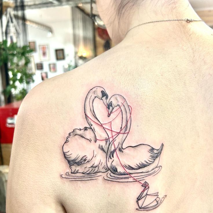 a woman's back with two swans on it and a heart in the middle