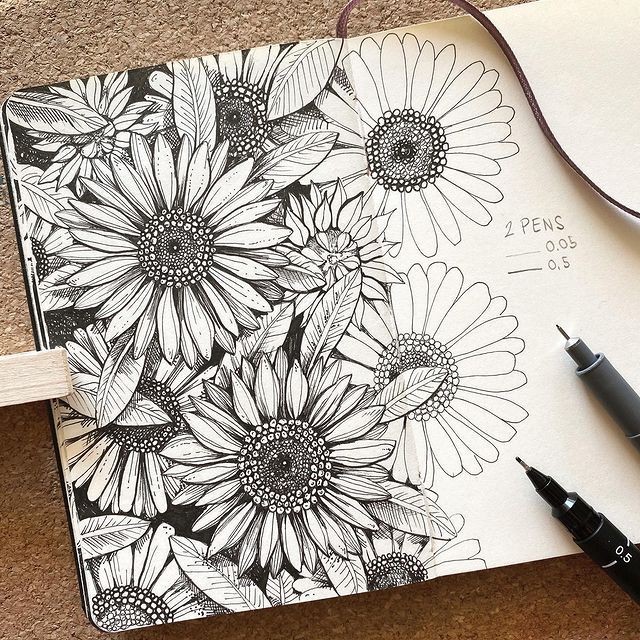 a notebook with flowers drawn on it next to a pair of glasses and a pen