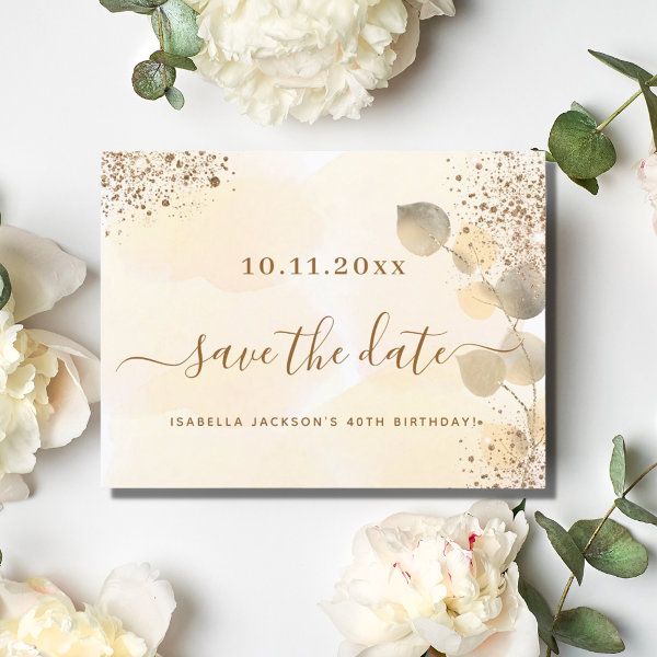 wedding save the date card with white flowers and greenery around it on a table