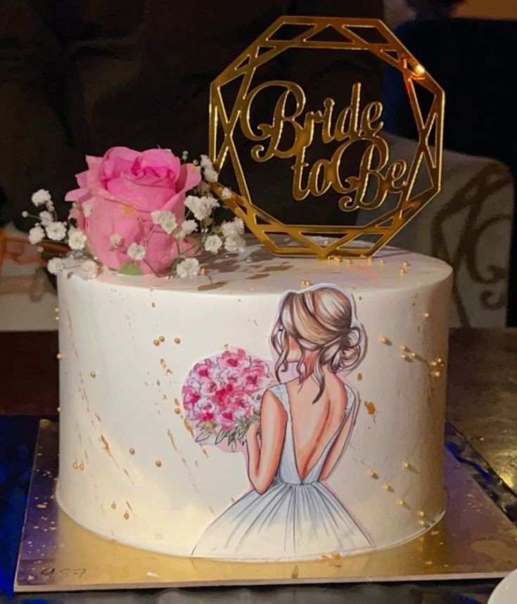 a wedding cake decorated with flowers and a bride to be sign