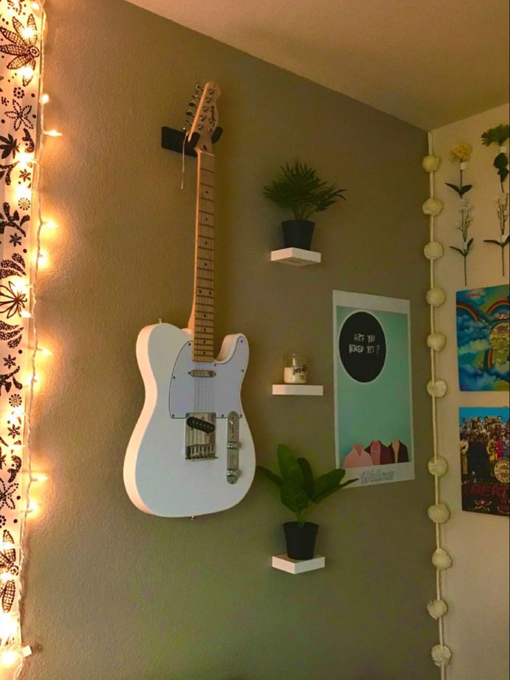 a guitar is hanging on the wall next to a potted plant and some lights