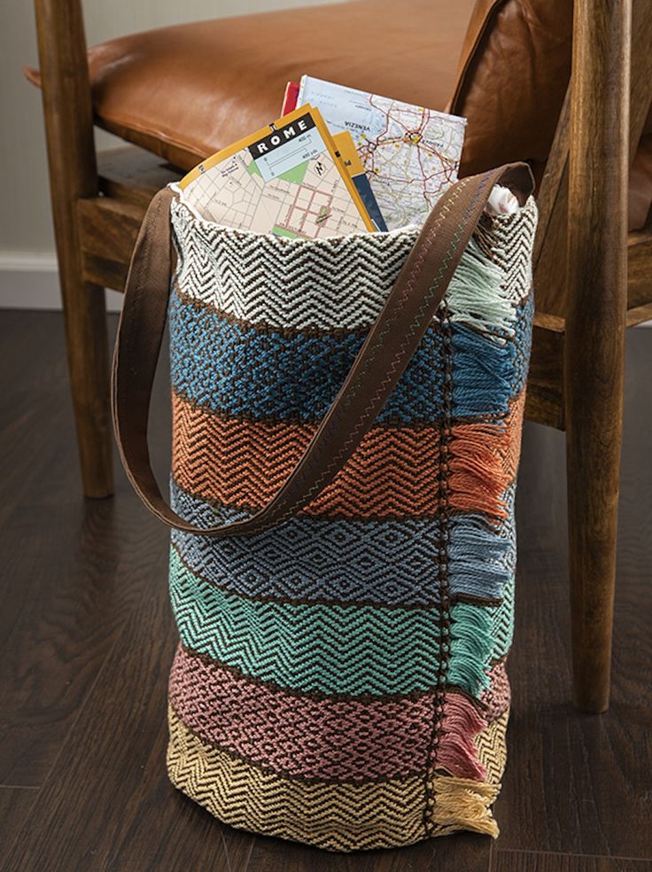 a multicolored bag sitting on the floor next to a wooden chair with a map in it