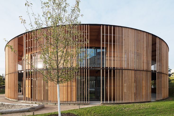 the circular building has wooden slats on it's sides and is surrounded by green grass