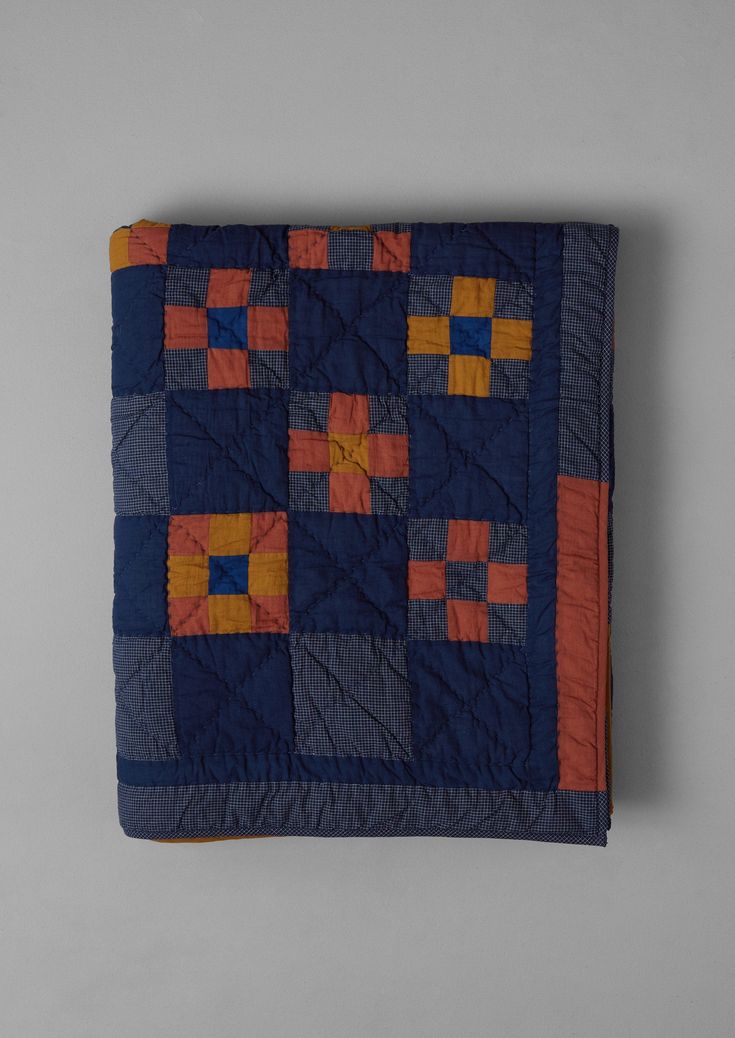 a blue and orange quilt with squares on it's side, sitting on a gray surface