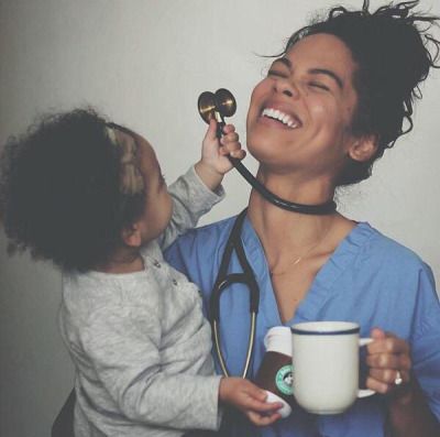 a woman with a stethoscope on her neck is holding a baby and smiling